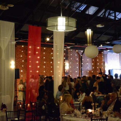 Paper Lanterns hanging over the main floor with a section of String Lights hanging vertically against a wall for a wedding at 26 Bridge (Brooklyn, NY)