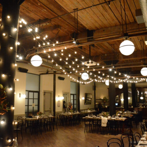 String lights G50 bulbs suspended in a V-Shaped pattern and wrapped around a column for a wedding at The Wythe Hotel located in Brooklyn New York