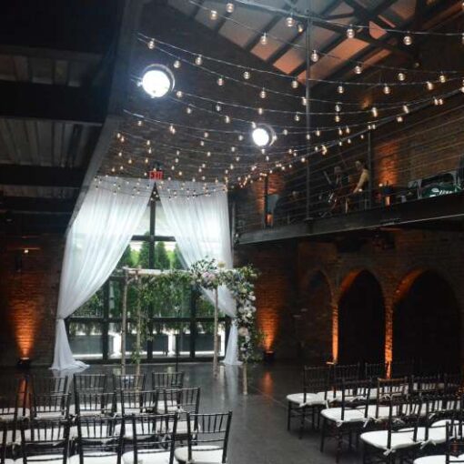 String Lights above the main floor with warm white up-Lights along the perimeter walls in the main room at The Foundry.
