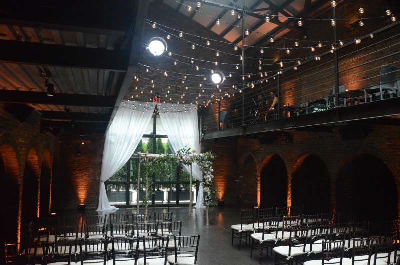 String Lights above the main floor with warm white up-Lights along the perimeter walls in the main room at The Foundry.
