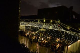 A canopy of String Lights suspended under tent frame in the rear courtyard at The Foundry located in Long Island City, New York