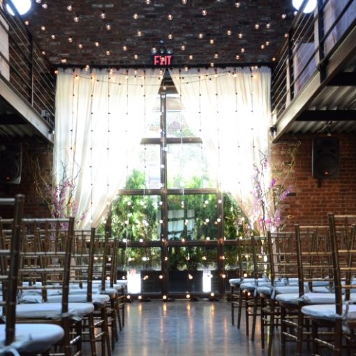 String Lights suspended overhead and vertically as a backdrop for a wedding ceremony in the main room at The Foundry located in Long Island City, New York