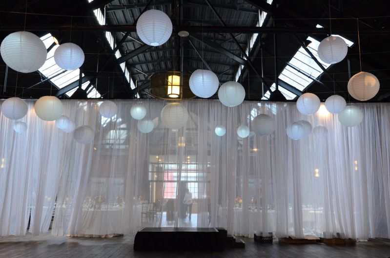 26 Bridge (Brooklyn, New York) - 25 Paper Lanterns each with a decorative LED light to provide a soft glow suspended over the ceremony with a white shear partitioning curtain.