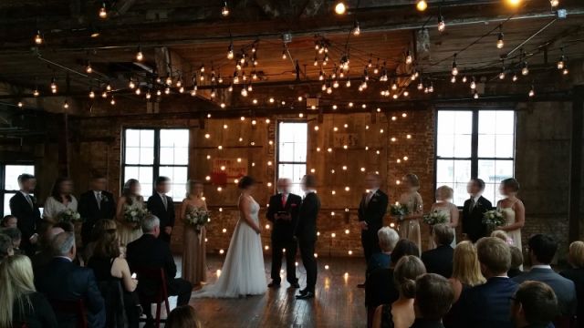 String Lights suspended vertically as a backdrop behind ceremony and overhead at The Greenpoint Loft located in Brooklyn, New York