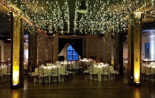 icicle fairy lights suspend over dance floor with up-lights at the base of columns for a wedding reception a The Liberty Warehouse located in Brooklyn New York