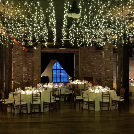 icicle fairy lights suspend over dance floor with up-lights at the base of columns for a wedding reception a The Liberty Warehouse located in Brooklyn New York