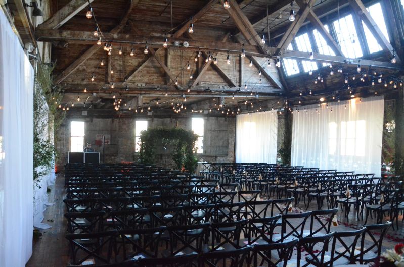 String Lights suspended between center columns with white sheer curtains partitioning the ceremony area at The Greenpoint Loft