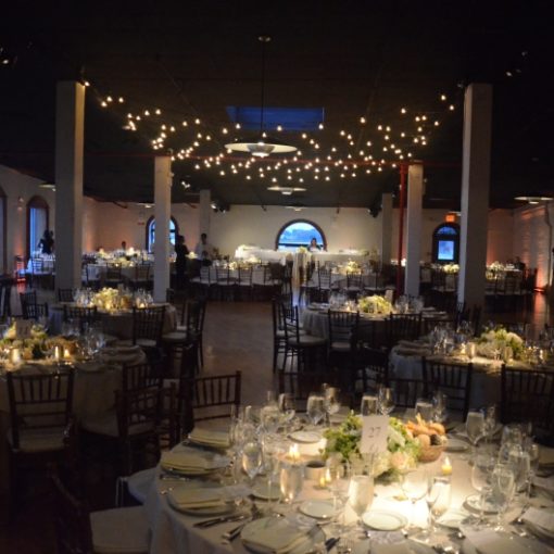 A canopy of string lights suspended over dance floor with pinspots focused on table center pieces