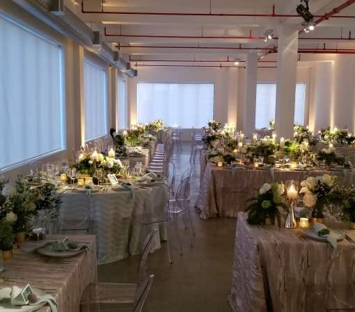 Pinspots focused on floral centerpieces with warm white Up-Lights along the perimeter walls at The Bordone