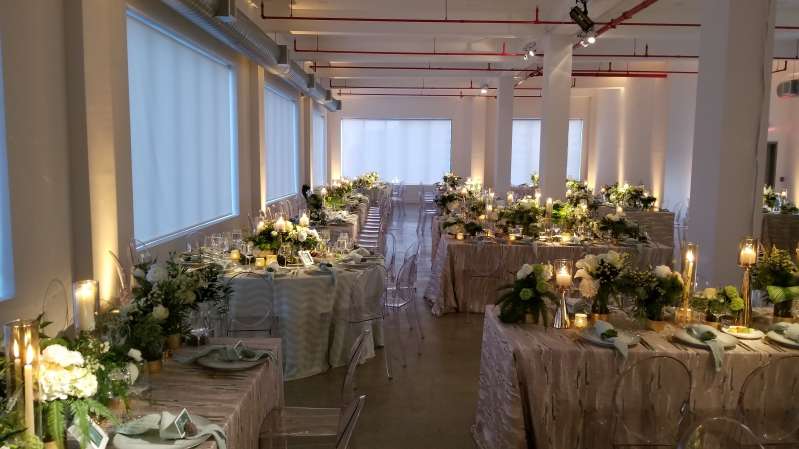 Pinspots focused on floral centerpieces with warm white Up-Lights along the perimeter walls at The Bordone