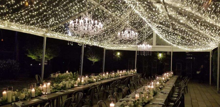 Mini-LED string lights also known as Twinkle Lights hanging under A clear top tent with crystal chandeliers in the courtyard at The Foundry.