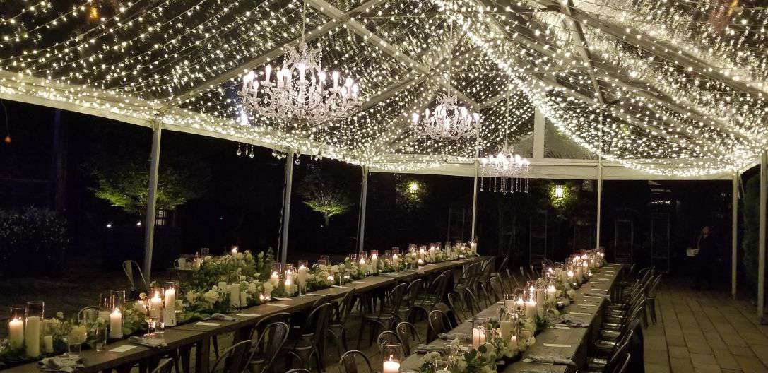 Mini-LED string lights also known as Twinkle Lights hanging under A clear top tent with crystal chandeliers in the courtyard at The Foundry.