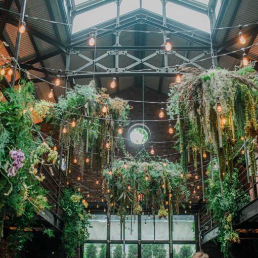 Zigzagging String Lights suspended in the main room with up-lights along the perimeter walls for a wedding reception at The Foundry.