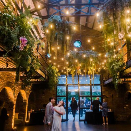 Zigzagging String Lights suspended in the main room with up-lights along the perimeter walls for a wedding reception at The Foundry.