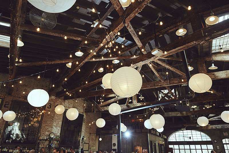 String Lights with white paper lanterns hanging above the main room for a wedding reception at The Houston Hall located in New York City