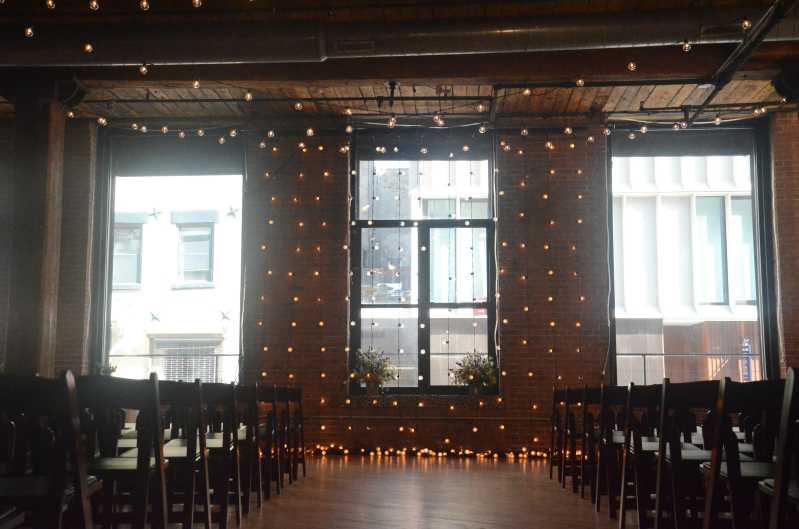 String lighting hanging betweeen the center columns along with string lights hanging vertically behind ceremony