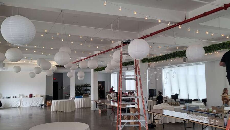 String Lights hanging above the 3rd-floor reception room along with paper lanterns hanging over the dance floor at The Bordone (Long Island City, New York City)