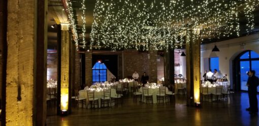 icicle fairy lights suspend over dance floor with up-lights at the base of columns for a wedding reception a The Liberty Warehouse located in Brooklyn New York