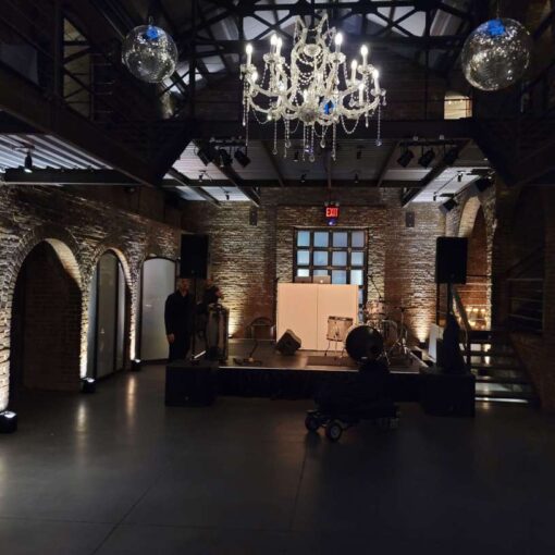 12ft x 12ft stage in the main room at the foundry with a crystal chandelier., mirror balls and Up-Lights along the perimeter walls