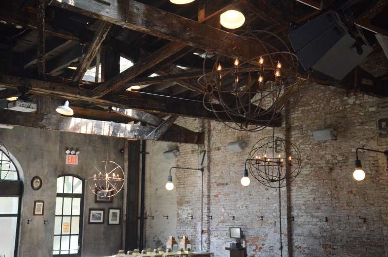 Bronze orb chandeliers hanging above the dinner tables for a wedding at The Houston Hall