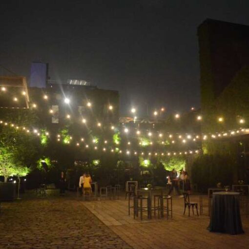 Bistro Lighting with Warm White bulbs suspended without lighting stands above the courtyard for a wedding at The Foundry.