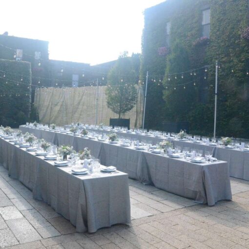 Café Lights with Warm White bulbs suspended above the courtyard with lighting stands for a wedding at The Foundry.