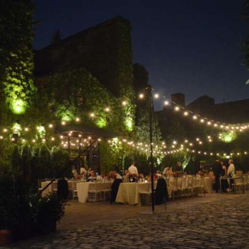 String Lighting with Warm White bulbs suspended above the courtyard with lighting stands for a wedding at The Foundry.