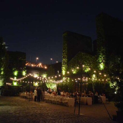 String Lighting with Warm White bulbs suspended above the courtyard with lighting stands for a wedding at The Foundry.