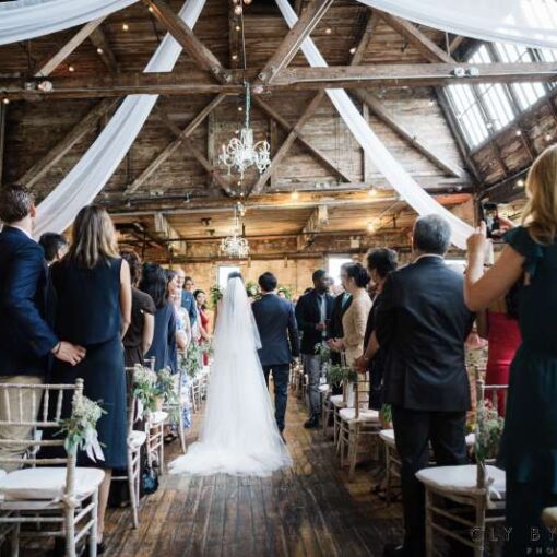 White sheer drapes hanging overhead with chandeliers and String Lights for a wedding at The Greenpoint Loft.