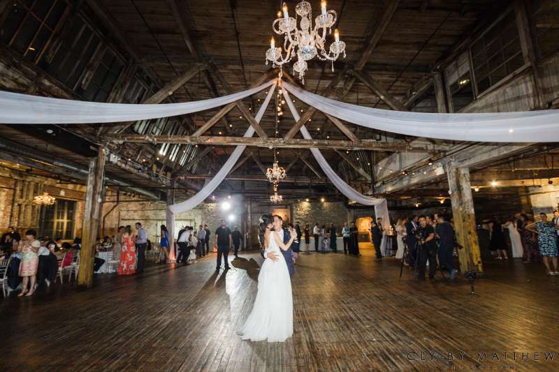 White sheer drapes hanging overhead with chandeliers and String Lights for a wedding at The Greenpoint Loft.