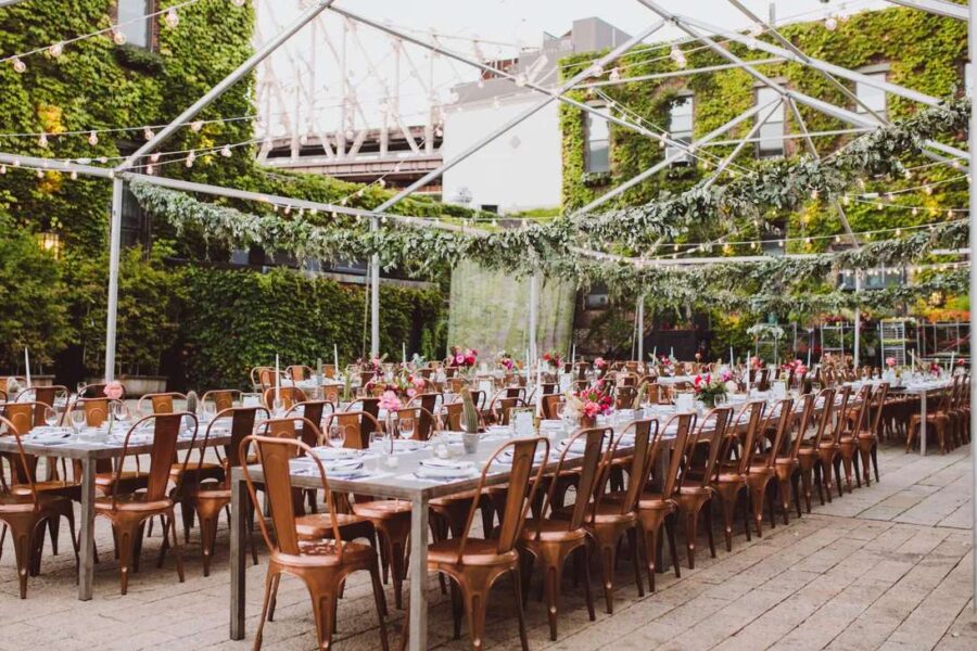 String Lights hanging under a raw tent frame with green florals for a wedding in the courtyard at The Foundry.