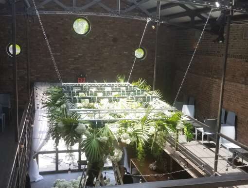 Florals attached to a rectangular truss hanging overhead in the main room for a wedding at The Foundry.