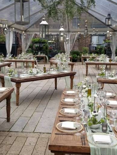 Silver stainless steel candle lanterns suspended under a clear top tent with hanging florals for a wedding reception at The Foundry.