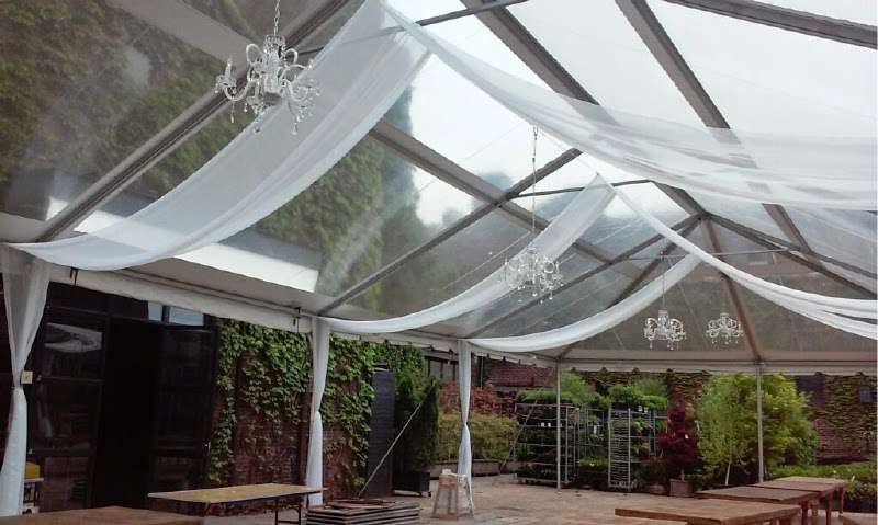 White sheer drapes hanging in parallel lines with Chrystal Chandeliers under a clear-top tent in the rear courtyard at The Foundry.