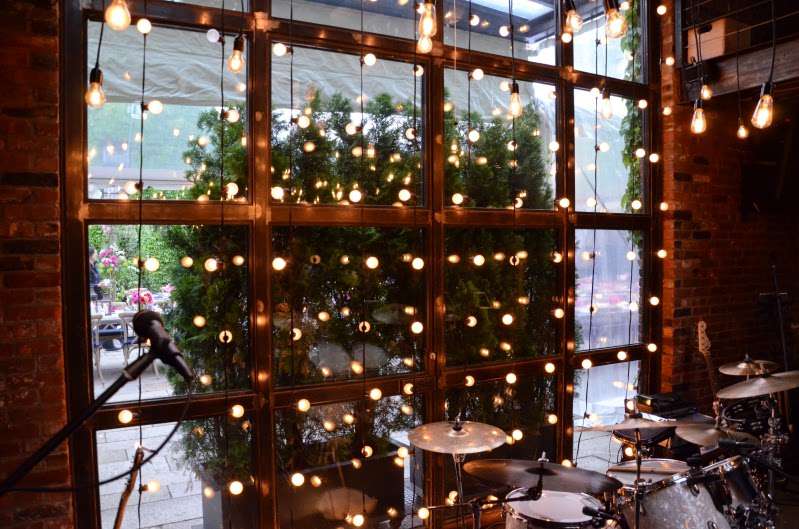 Warm White String Lights hanging vertically as a backdrop in the main room at the rear courtyard doors