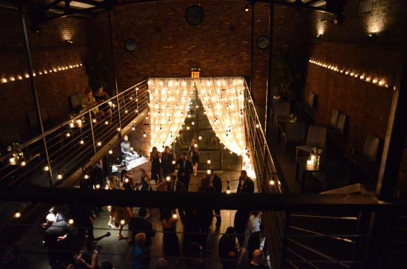 Warm White String Lights are hanging overhead above the main floor and vertically at the rear courtyard doors for a wedding at The Foundry.