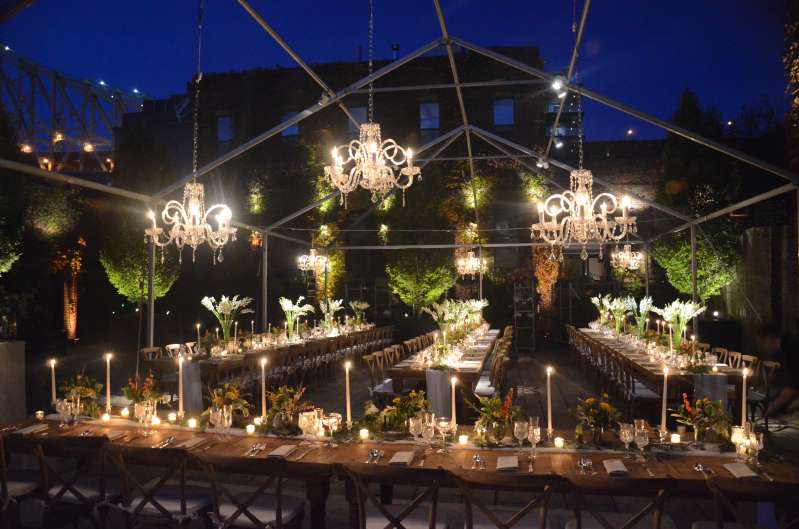 Crystal chandeliers and pin-spots are hanging on a raw tent frame for an outdoor wedding in The Courtyard at The Foundry.