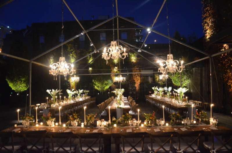 Crystal chandeliers and pin-spots are hanging on a raw tent frame for an outdoor wedding in The Courtyard at The Foundry.