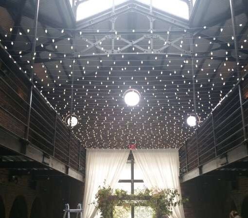 A canopy of warm white String Lights hanging across the mezzanine level in the main room for a wedding at The Foundry.