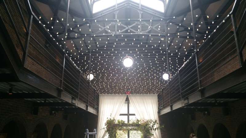 A canopy of warm white String Lights hanging across the mezzanine level in the main room for a wedding at The Foundry.