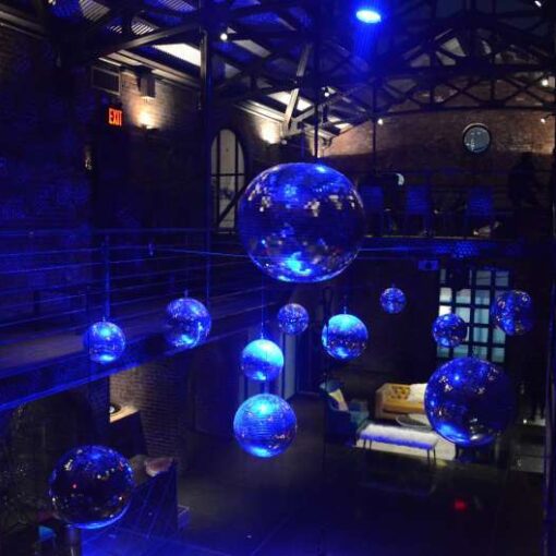 A cluster of mirror balls hanging above the main room with a color wash for The Planners Dining Club hosted by Jove Meyer of Jove Meyer Events.