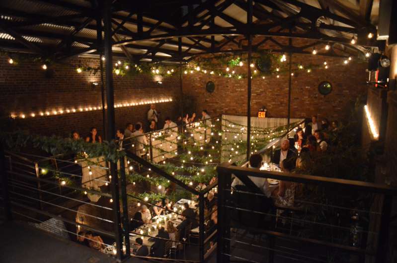 String lights with florals hang from the railing of the mezzanine level and from the ceiling above the mezzanine level in the main room at The Foundry.