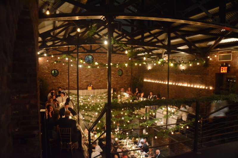 String lights with florals hang from the railing of the mezzanine level and from the ceiling above the mezzanine level in the main room at The Foundry.