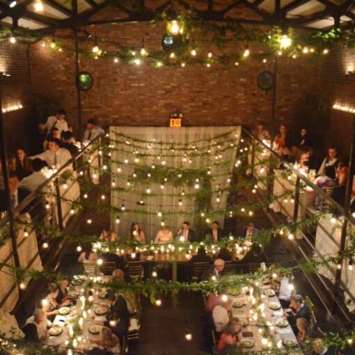 String lights with florals hang from the railing of the mezzanine level and from the ceiling above the mezzanine level in the main room at The Foundry.