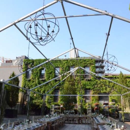 Orb Chandeliers hanging under a raw tent frame in the courtyard for a wedding at The Foundry.