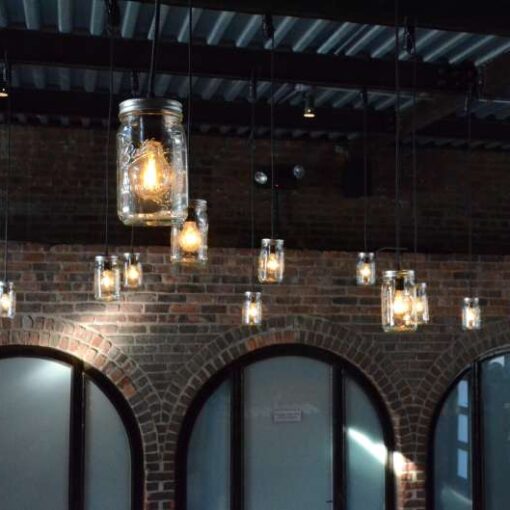 Warm white Pendant Lamps each with a Mason Jar hanging under the mezzanine level for a wedding in the main room at The Foundry.