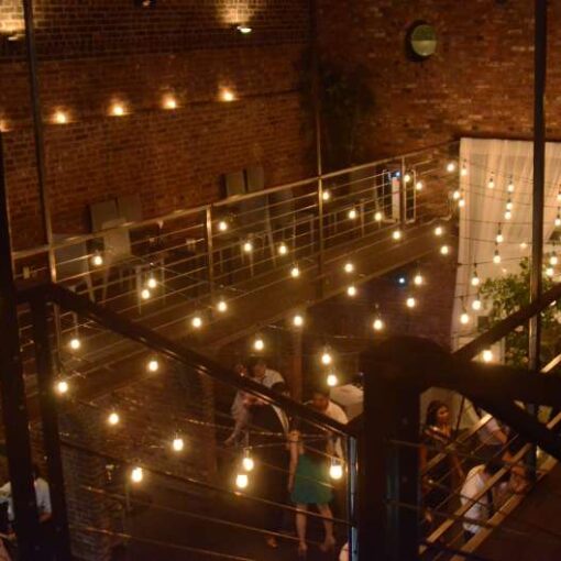 Warm White String Lights hanging in the main room across the mezzanine level for a wedding at The Foundry