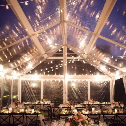 String lighting with warm white bulbs hangs in random zigzagging lines under a tent in the courtyard at The Foundry for a wedding.