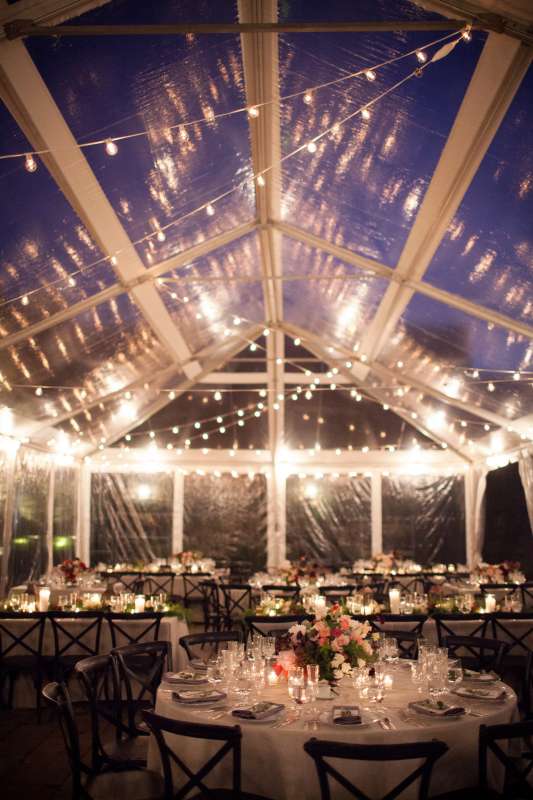 String lighting with warm white bulbs hangs in random zigzagging lines under a tent in the courtyard at The Foundry for a wedding.