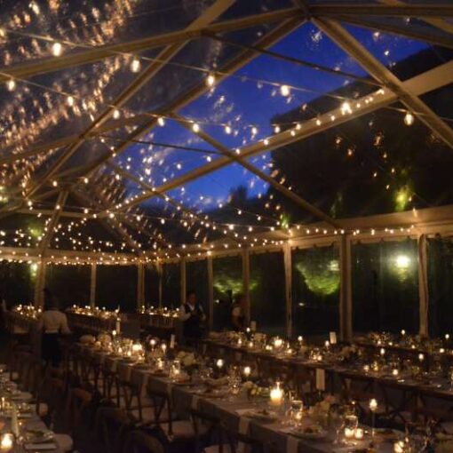 String lighting with warm white bulbs hangs in random zigzagging lines under a tent in the courtyard at The Foundry for a wedding.